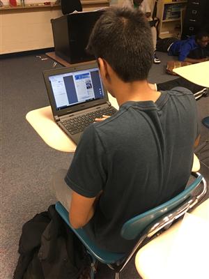 Student sitting in a desk working on a laptop 